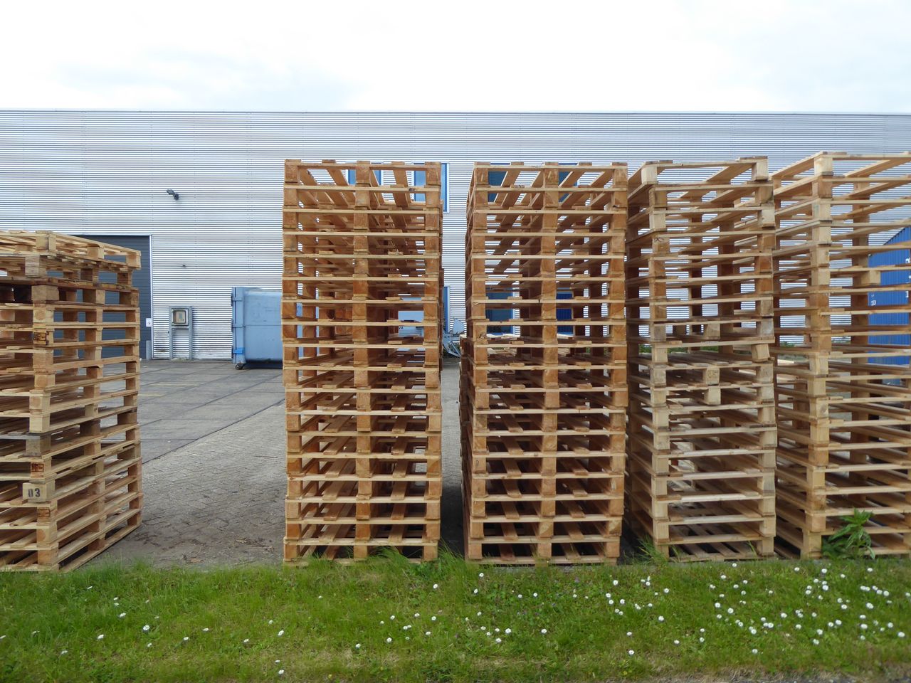 Rows of wooden pallets stacked outdoors near a warehouse, perfect for industrial and logistics themes.